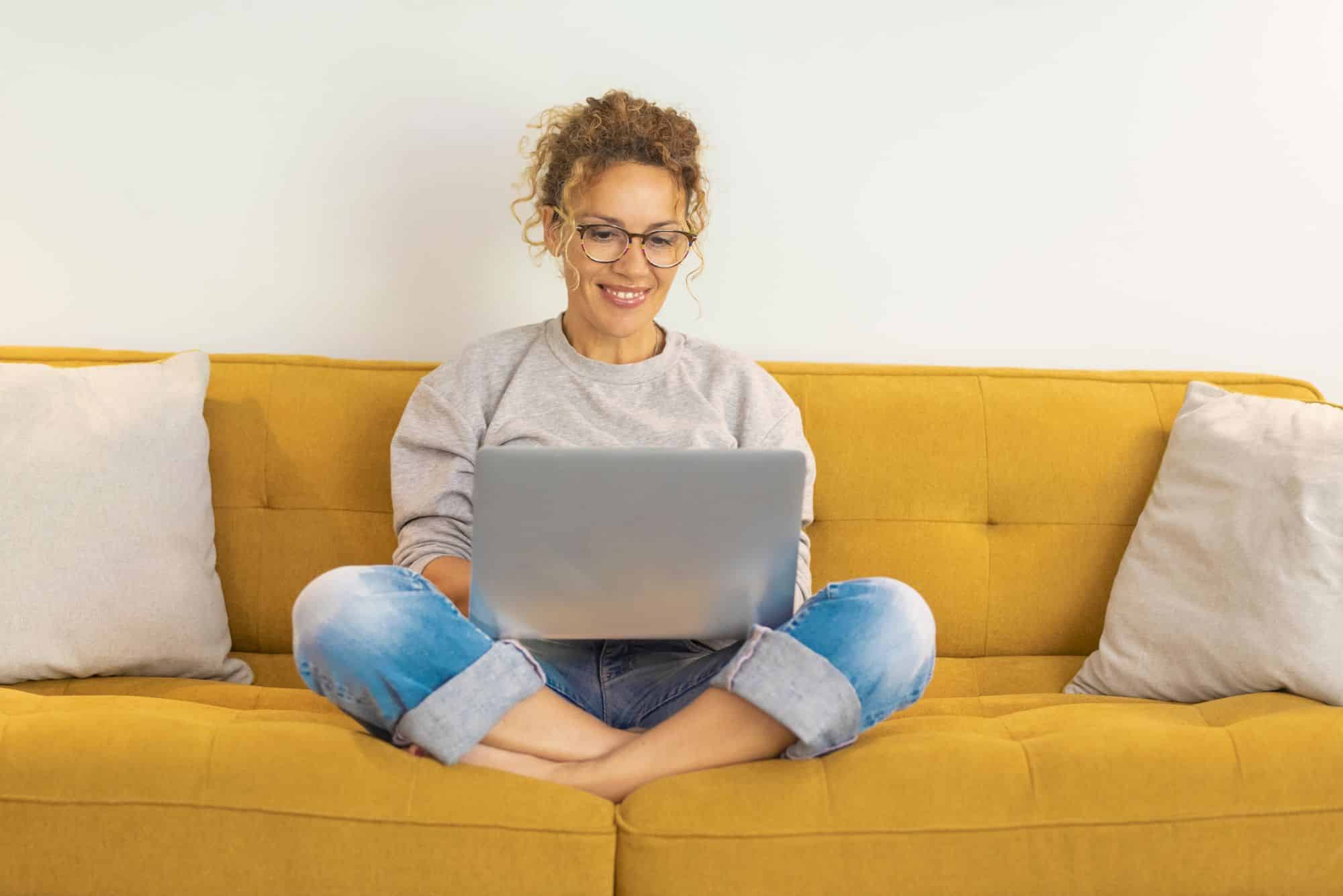 lady sitting on sofa using laptop to take free online neurodivergent quiz